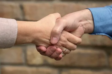 Handschlag vor einer Ziegelwand
